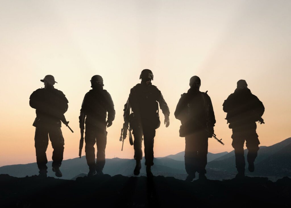 Military silhouettes of soldiers against the backdrop of sunset sky