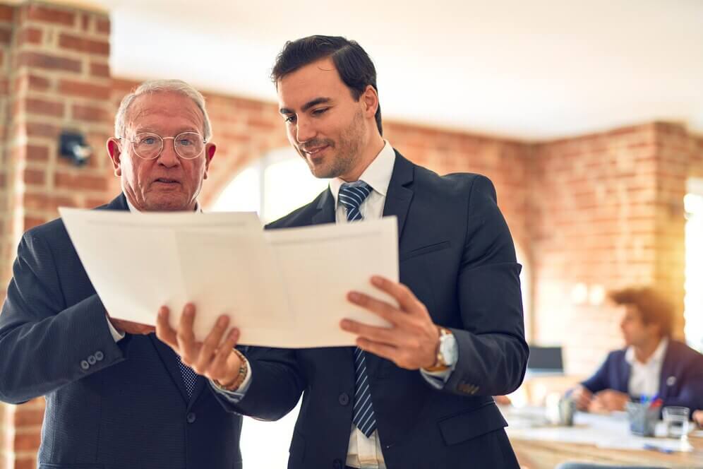 two men in suits reviewing documents in an office