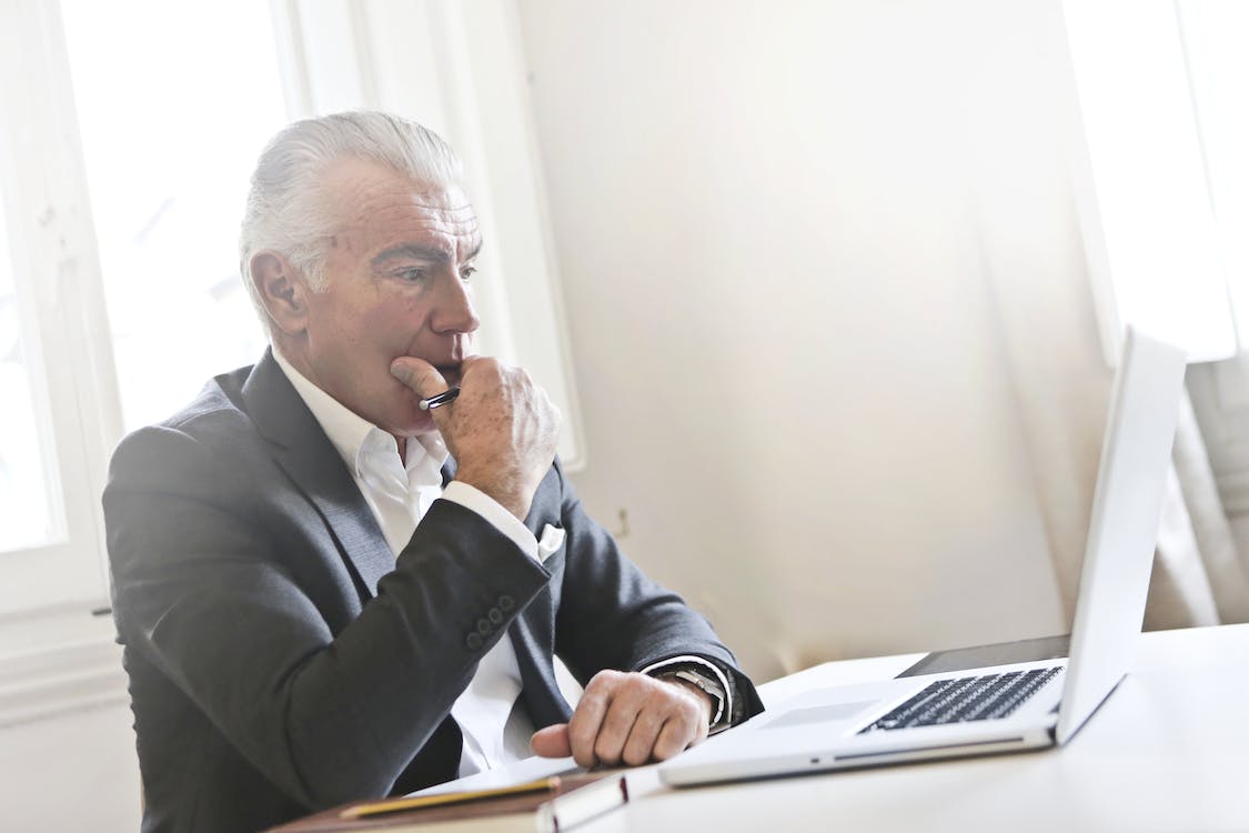 man wearing suit staring at a laptop