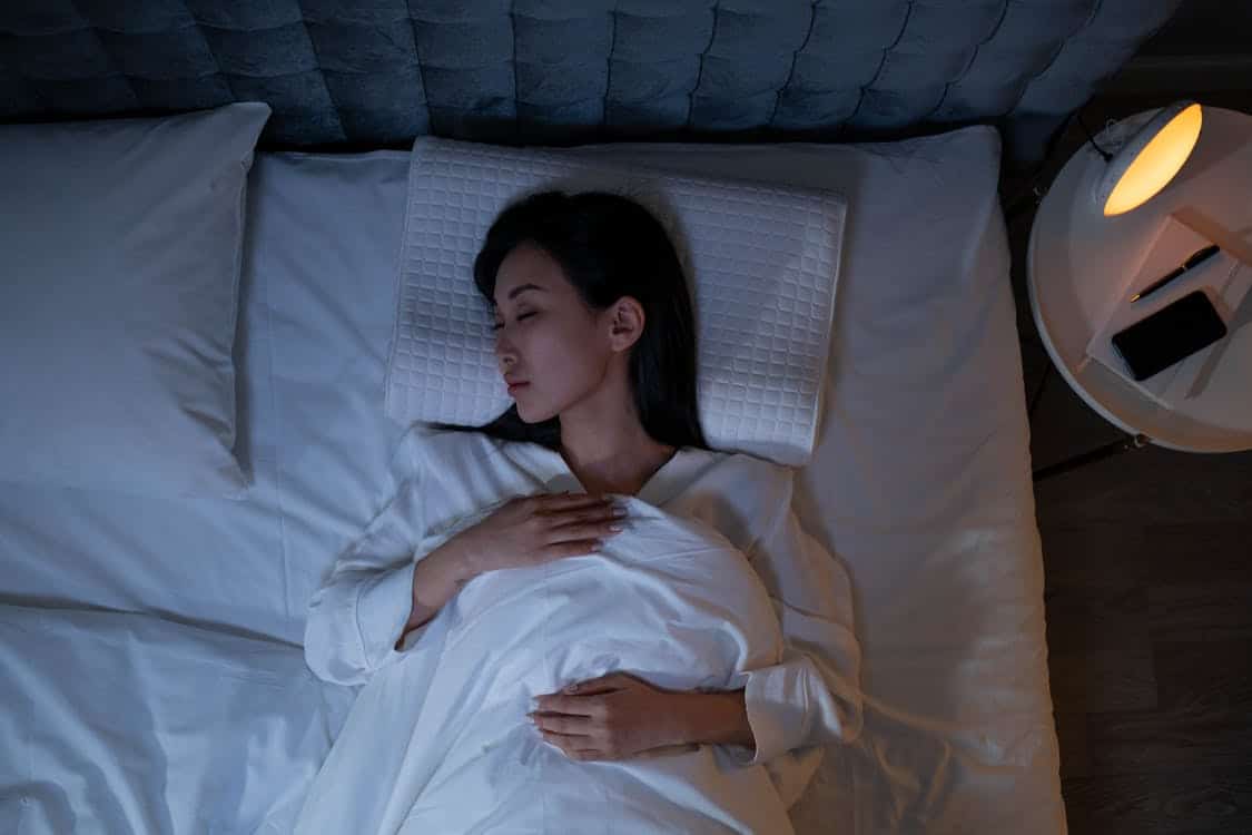 woman deeply asleep on a clean white sheet