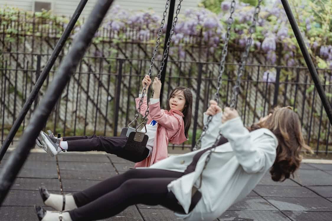 woman and young girl playing in the swing